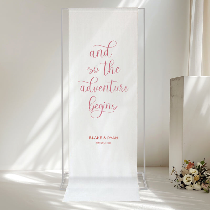 Wedding linen welcome sign with 'And so the adventure begins' quote and bride and grooms names. Printed in Australia. Pink and orange.