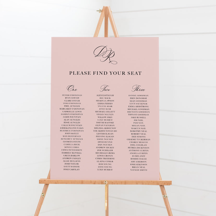 Traditional calligraphy wedding seating chart or guest name plan with monogram of bride and grooms initials. Dusty pink with 3 long tables.