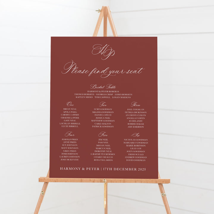 Traditional calligraphy wedding seating chart or guest name plan with monogram of bride and grooms initials. Dusty red and white colours.